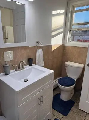 a bathroom with a sink and a toilet and a window at For NYC visitors 9min to NYC train-15min to EWR in Bayonne