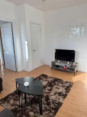a living room with a table and a tv at For NYC visitors 9min to NYC train-15min to EWR in Bayonne