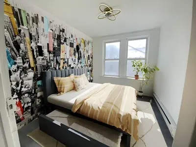 a bedroom with a bed and a wall of pictures at Manhattan Skyline Mins to TimeSQ in West New York