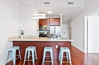 a kitchen with three bar stools and a counter top at High-End 1BR with Rooftop Amenities in Philadelphia
