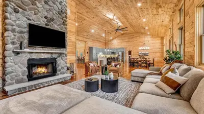a living room with a fireplace and a stone wall at Grand Timber by AvantStay Indoor Pool Sports Court Game Room More in White Haven