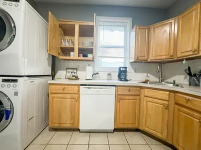 a kitchen with wooden cabinets and a white dishwasher at 3 bed 1 bath FREE parking near NYC in North Bergen