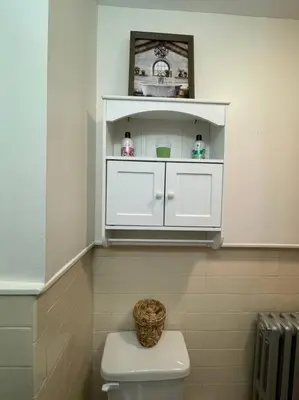 a bathroom with a white cabinet above a toilet at House of the Heart at Trolley Square! in Wilmington