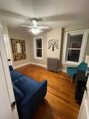 a living room with a blue couch and a ceiling fan at House of the Heart at Trolley Square! in Wilmington