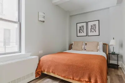 a bedroom with a bed with an orange blanket at Blueground Upper West Side ac wd NYC-1546 in New York