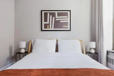 a bed with white sheets and a picture above it at Blueground Gramercy Park 2bd apartment NYC-1616 in New York