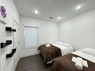 a white bedroom with two beds and a window at Stunning NYC rooftop views minutes away from NYC 2 bedroom 2 bath in Jersey City