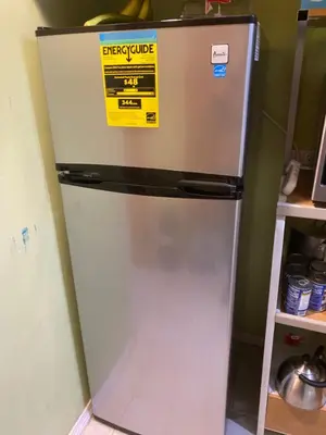 a refrigerator in a kitchen with a yellow sign on it at Cozy charming private studio in North Bergen