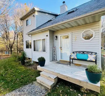 a house with a wooden porch with a bench on it at Cozy Cottage by the Lake in Albrightsville