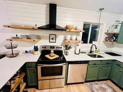 a kitchen with green cabinets and a stove top oven at Cozy Cottage by the Lake in Albrightsville