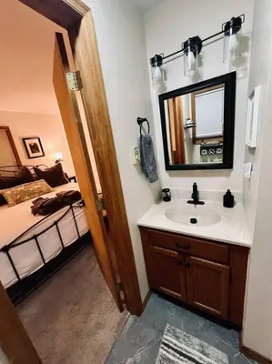 a bathroom with a sink and a mirror and a bed at Cozy Cottage by the Lake in Albrightsville