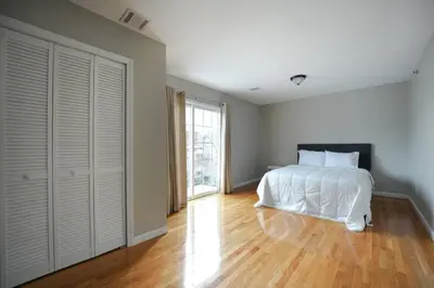 a bedroom with a white bed and a large window at Newark Liberty Brick House - Private Bedroom 1 in Newark