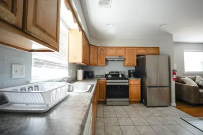 a kitchen with wooden cabinets and a stainless steel refrigerator at Newark Liberty Brick House - Private Bedroom 2 in Newark