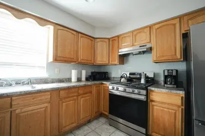 a kitchen with wooden cabinets and a stove top oven at Newark Liberty Brick House - Private Bedroom 2 in Newark