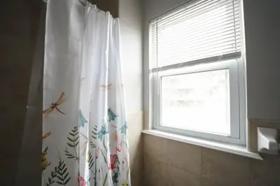 a bathroom with a shower curtain and a window at Newark Liberty Brick House - Private Bedroom 3 in Newark