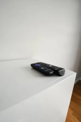 a remote control sitting on top of a white table at Newark Liberty Brick House - Private Bedroom 3 in Newark