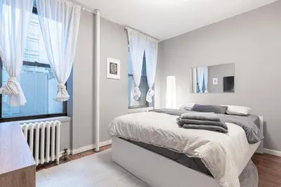 a white bedroom with a bed and a window at Charming 3Bd in Manhattan in New York