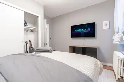 a white bedroom with a bed and a tv on the wall at Charming 3Bd in Manhattan in New York