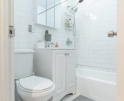 a white bathroom with a toilet and a bath tub at Charming 3Bd in Manhattan in New York
