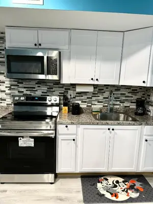 a kitchen with white cabinets and a sink and a microwave at A Temporary Haven in Newark