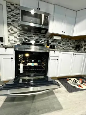 an open oven in a kitchen with a microwave at A Temporary Haven in Newark