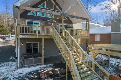 a house with a wrap around porch with a deck at New Luxury Lakeview Retreat with Lake Access, HotTub, Game Room, Sleeps 28 in Lake Harmony