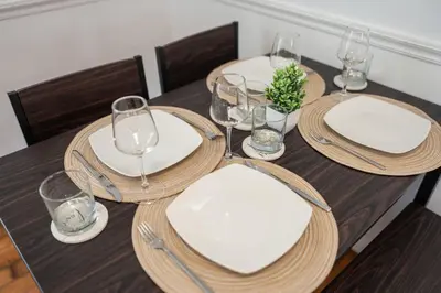 a wooden table with white plates and wine glasses at Stylish Apartment - Light Rail Access in Bayonne