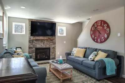 a living room with a couch and a large clock at Arrowhead Lake Access and Fire Pit Serene Cottage in Pocono Lake