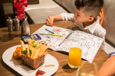 a young boy sitting at a table with a plate of food at The Knickerbocker in New York