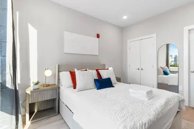a white bedroom with a bed and a mirror at Stunning 1-BD - City Views - Near Fishtown in Philadelphia