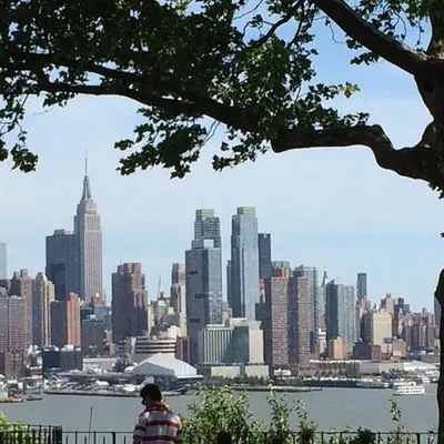 a person sitting on a bench looking at a city at Private Room C West NY, NJ 12 mints from NYCity Times Square in West New York