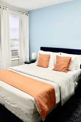 a bedroom with a large bed with orange and white pillows at Private Room C West NY, NJ 12 mints from NYCity Times Square in West New York