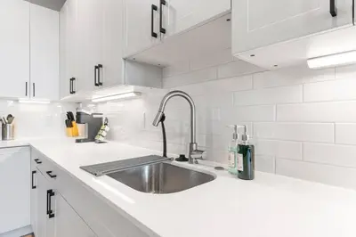 a kitchen with a sink and white cabinets at Near Fishtown and Old City - King Bed - City Views in Philadelphia
