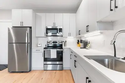 a kitchen with white cabinets and a stainless steel refrigerator at Near Fishtown and Old City - King Bed - City Views in Philadelphia