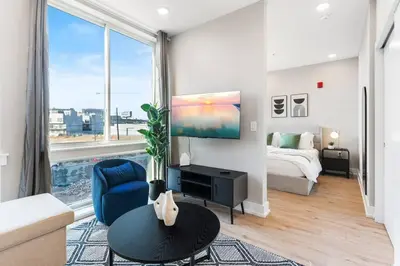 a living room with a bed and a large window at Waterfront Studio - Near Fishtown and Old City in Philadelphia