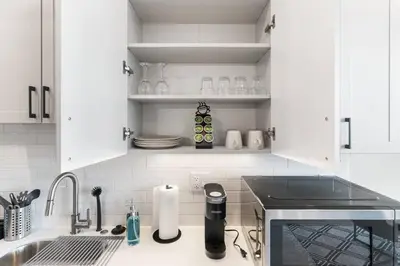 a white kitchen with white cabinets and a sink at Waterfront Studio - Near Fishtown and Old City in Philadelphia