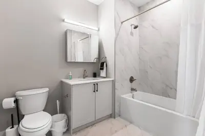 a white bathroom with a toilet and a tub and a sink at Waterfront Studio - Near Fishtown and Old City in Philadelphia