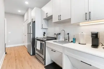 a kitchen with white cabinets and stainless steel appliances at Waterfront Studio - Near Fishtown and Old City in Philadelphia