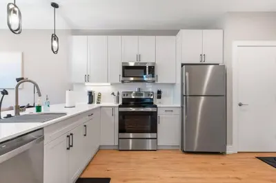 a kitchen with white cabinets and a stainless steel refrigerator at Sleeps 6 - Pier Views - Near Fishtown and Old City in Philadelphia