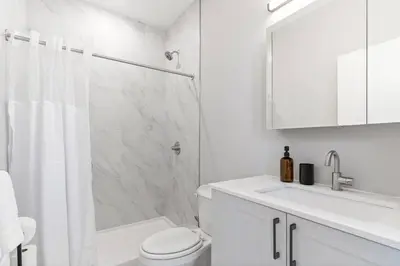 a white bathroom with a shower and a toilet and a sink at Sleeps 6 - Pier Views - Near Fishtown and Old City in Philadelphia