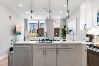 a white kitchen with a sink and a window at Sleeps 6 - Pier Views - Near Fishtown and Old City in Philadelphia