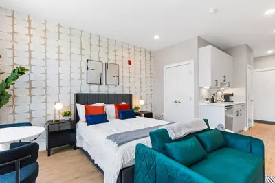 a bedroom with a bed and a blue couch at Charming Studio with Breathtaking Pier and Bridge Views in Philadelphia