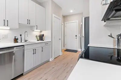 a kitchen with white cabinets and a black refrigerator at Charming Studio with Breathtaking Pier and Bridge Views in Philadelphia