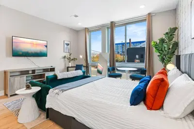 a bedroom with a large bed and a living room at Charming Studio with Breathtaking Pier and Bridge Views in Philadelphia