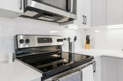 a stove top oven in a kitchen with white cabinets at 1BD Sleeps 4 with Views - Near Fish Town and Old City in Philadelphia