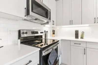 a white kitchen with a stove and a microwave at Modern 1-BD - Pier Views - Near Old City in Philadelphia
