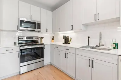 a white kitchen with a stove and a microwave at 1BD - Sleeps 4 - Harbor Views - Near Fish Town- in Philadelphia