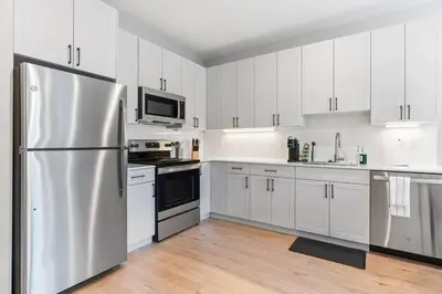 a kitchen with white cabinets and a stainless steel refrigerator at 1BD - Sleeps 4 - Harbor Views - Near Fish Town- in Philadelphia