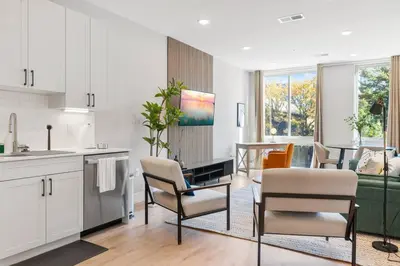 a kitchen and living room with white cabinets and chairs at King Bed - Stunning Pier Views - Near Fishtown in Philadelphia