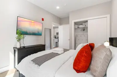 a bedroom with a large white bed with orange pillows at Amazing City Views - Sleeps 6 - Near Fishtown in Philadelphia